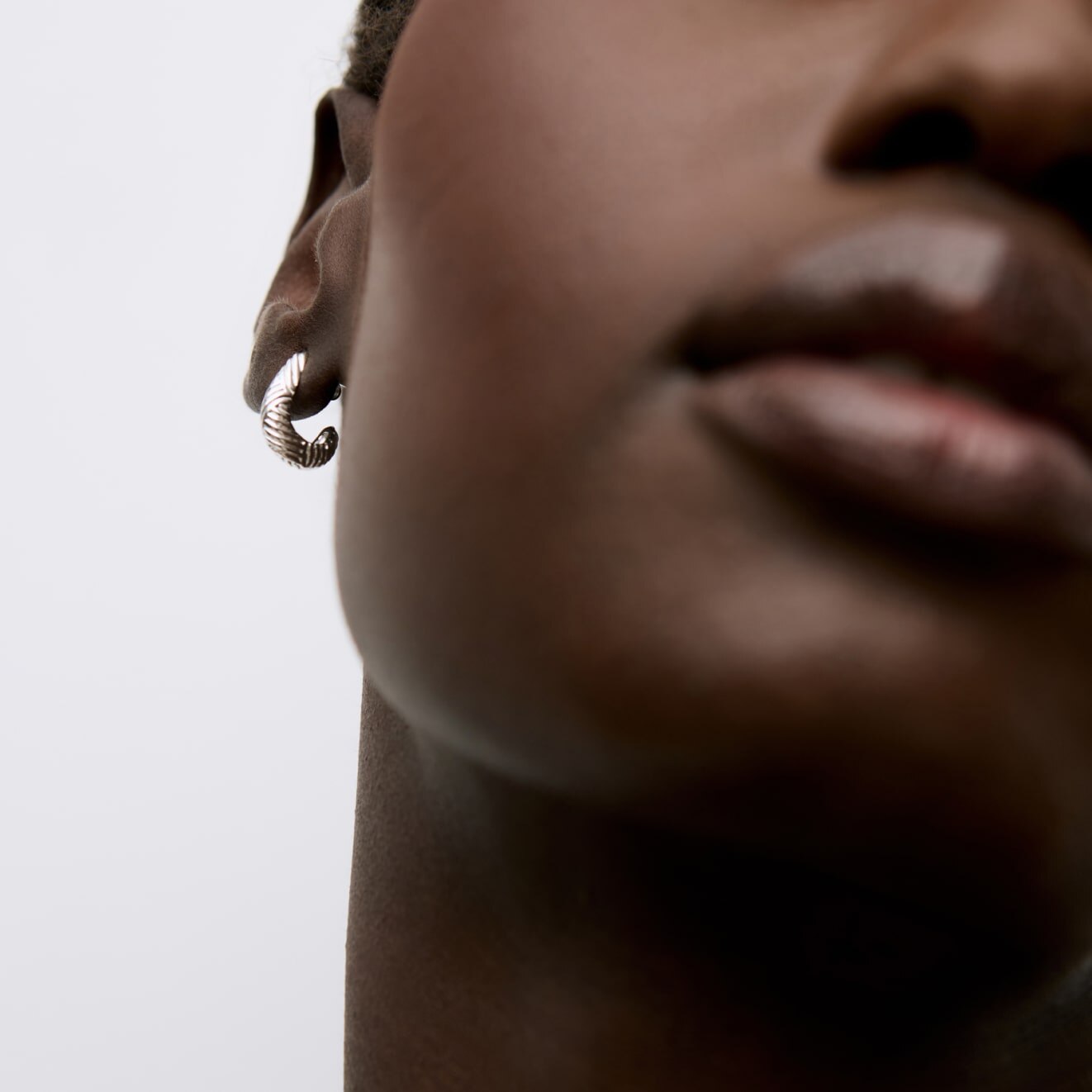 Model wearing a silver oval stud earring 